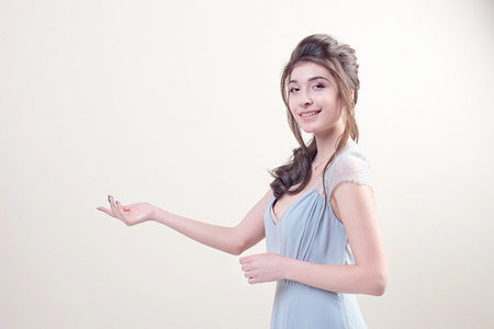 Young woman wearing in luxurious long lacy dress pointing at empty copy space isolated on backgroundの写真素材