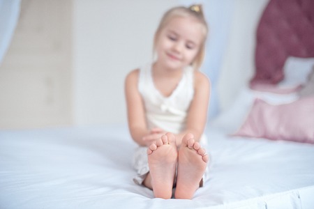 Little blonde girl sitting on the bedの写真素材