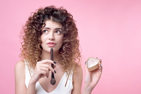 Close-up of a young caucasian woman holding brush and blush palette.の写真素材
