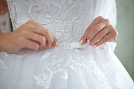 Close-up female hands in focus with blurred slim waist body on background.の写真素材