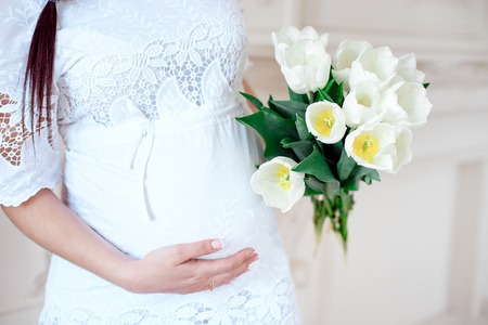 Close-up pregnant woman in white room.の写真素材