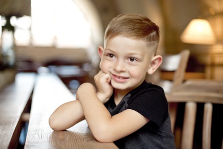 little boy 4-5 years old sitting at the wooden table in cafeの写真素材