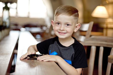 little boy with smartphone sitting at the tableの写真素材