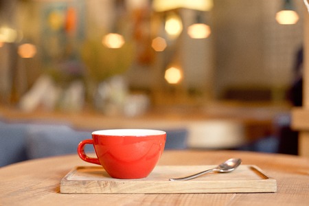coffee cup on wooden tray in modern cafe interior with blurred background.の写真素材