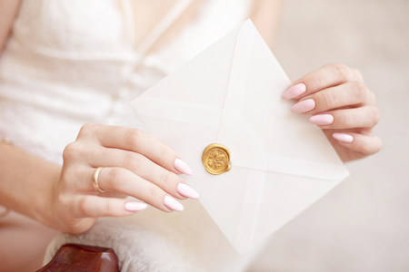 close-up woman with slim body holding invitation envelope card in hands.の写真素材