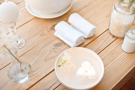 spa set with candles in aroma bath and rolled towels on wooden tableの写真素材