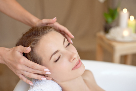 Woman face with perfect skin doing facial massage in a bathtubの写真素材