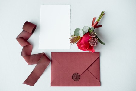 Wedding invitation as a decorated letter on a white tablecloth with a flower arrangement.の写真素材