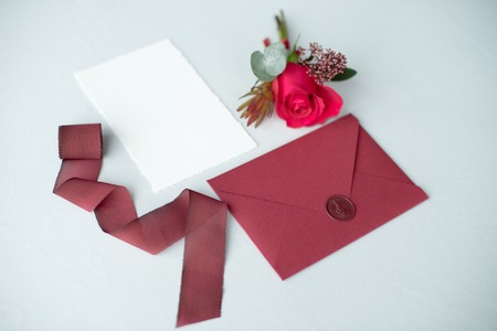 Wedding invitation as a decorated letter on a white tablecloth with a flower arrangement.の写真素材