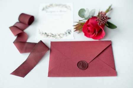 Wedding invitation as a decorated letter on a white tablecloth with a flower arrangement.の写真素材