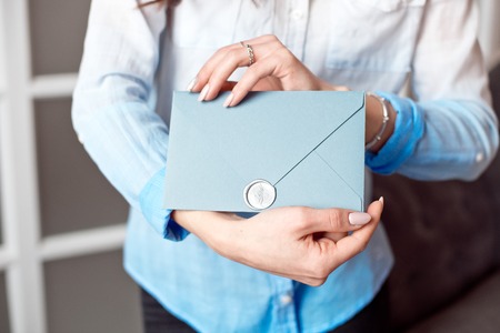 Close-up of a young girl holding a blue rectangular gift envelope with invitations, goods and services card.の写真素材