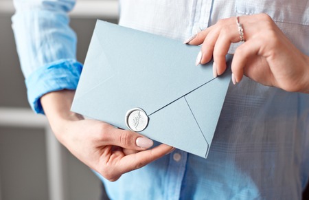 Close-up of a young girl holding a blue rectangular gift envelope with invitations, goods and services card.の写真素材