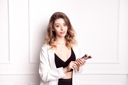 Beautiful young girl with brown hair in her hands holding a professional makeup brushの写真素材
