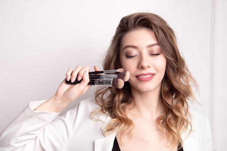 Cute brunette make-up artist using makeup brush.の写真素材