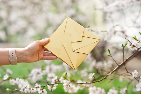 Close-up woman hand holding invitation card golden color, front view.の写真素材