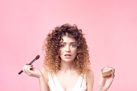 Beautiful young woman applying foundation powder or blush with makeup brush.の写真素材