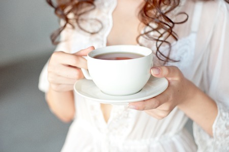 Close-up of a white Cup of hot latte art coffee with a heart shape in the hands of a young girl.の写真素材