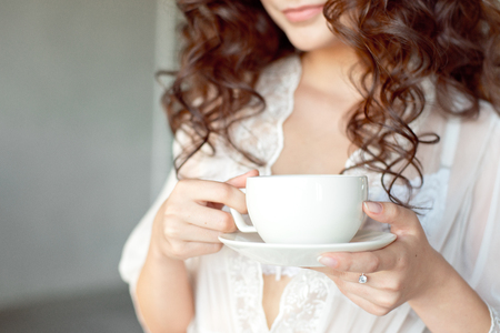 Close-up of a white Cup of hot latte art coffee with a heart shape in the hands of a young girl.の写真素材