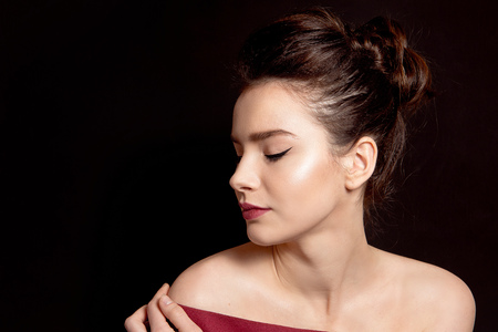 Close-up portrait of a woman with classic make-up with a black arrow and bare lip over her shoulders...