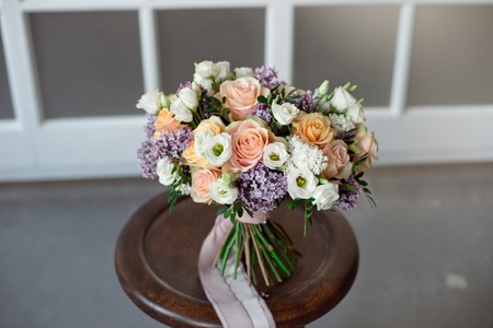 Vintage rustic bouquet of wild roses Carnations with green leaves of eucalyptus and thistle of lilac twigs on a light background.の写真素材