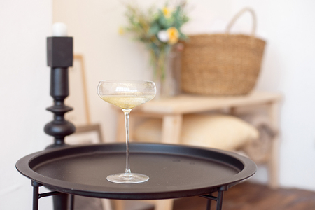 Full glass of champagne with white wine or champagne stands on a black matte tray in the room.の写真素材
