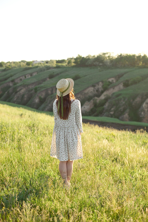 Happy woman with open arms stay on the peak of the mountain cliff edge under sunset light sky enjoying the success, freedom and bright future.の写真素材