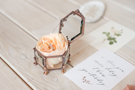 Wedding decor vintage glass square casket stand with peony rose inside and wedding ring invitation card.の写真素材
