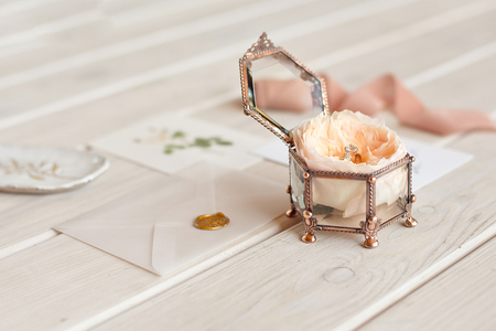 Wedding decor vintage glass square casket stand with peony rose inside and wedding ring invitation card.の写真素材