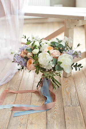 Close-up bouquet of roses peonies freesia dianthus flowers on the round white floore indoors.の写真素材