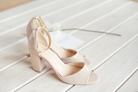 Wedding bouquet of white flowers, shoes and wedding rings on a wooden background.の写真素材