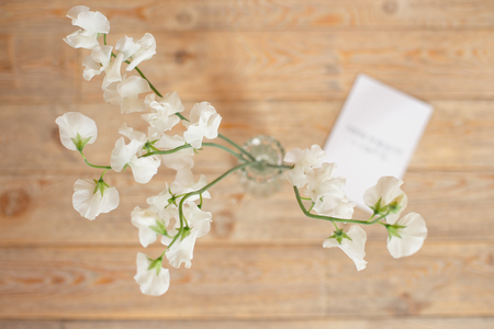 Wedding invitation birthday gift certificate for a spa or care decorated letter card on a white wooden table with a branch of white flowers.の写真素材