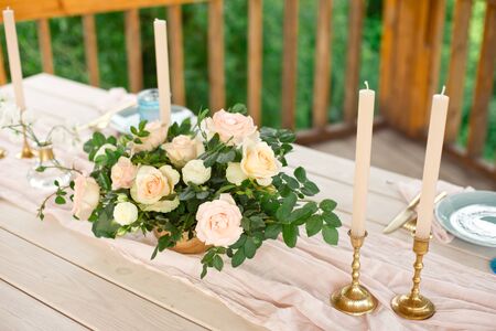 Decorated table for dinner for two person, with plates knife, fork, cheese, wine, wine glasses and flowers in a copper vaseの写真素材