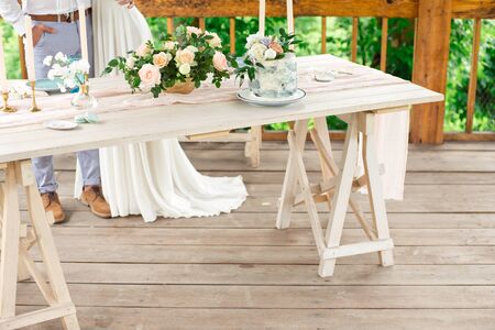 Decorated table for dinner for two person, with plates knife, fork, cheese, wine, wine glasses and flowers in a copper vaseの写真素材