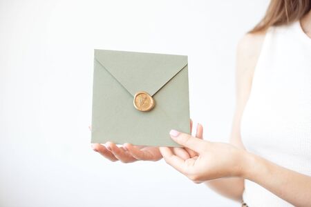 Close-up photo of female hands holding a silver blue or pink invitation envelope with a wax seal, a gift certificate, a postcard, a wedding invitation card.の写真素材