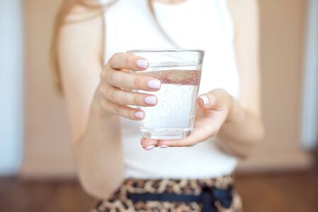 Female hands holding a clear glass of water.A glass of clean mineral water in hands, healthy drink.の写真素材