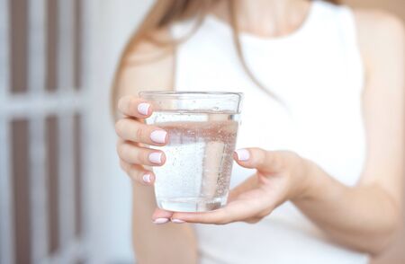 Female hands holding a clear glass of water.A glass of clean mineral water in hands, healthy drink.