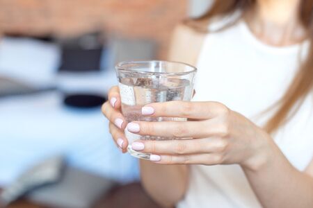 Female hands holding a clear glass of water.A glass of clean mineral water in hands, healthy drink.