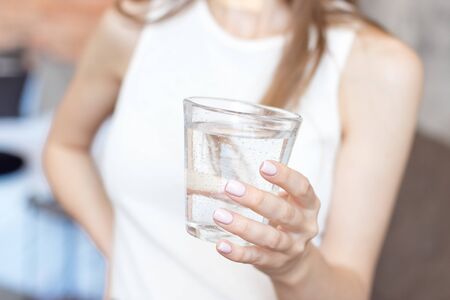 close-up woman with slim body holding a glass of water, rear veaw.