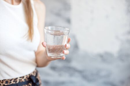 close-up woman with slim body holding a glass of water, rear veaw.