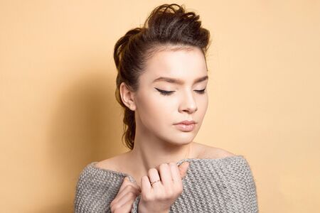 Young beautiful girl with dark hair with a hairstyle a high bunch of makeup, even skin tone with a black arrow and sparkles on her lips.の写真素材