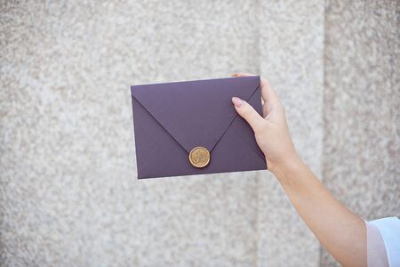 Young girl holds mail invitation cards in her hand. Envelopes with wax seal in hands close-up.の写真素材