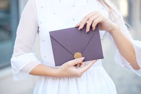 Young girl holds mail invitation cards in her hand. Envelopes with wax seal in hands close-up.