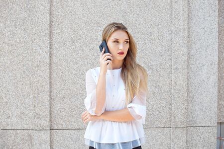 Attractive blonde businesswoman talking on a mobile phone or writes a message to a clientの写真素材