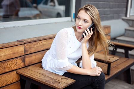 Charming woman with a beautiful smile speaks good news on a mobile phone while relaxing in a cafe, a happy Caucasian woman speaks on a mobile phone while relaxing in a cafe in her free time.の写真素材