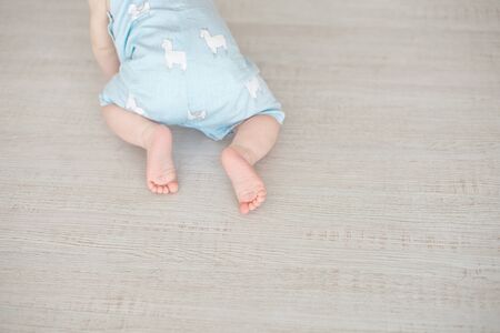 Adorable baby crawls on a wooden parquet.の写真素材
