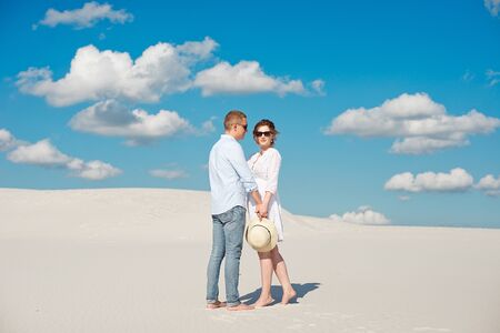 Young couple enjoying the sunset in the dunes. Romantic traveler walks in the desert. Adventure travel lifestyle conceptの写真素材