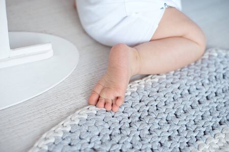 Cute baby in blue overalls sits on a knitted carpet.の写真素材