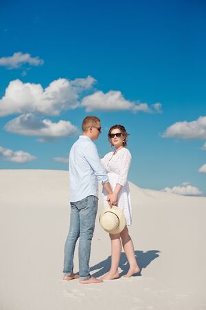 Young couple enjoying the sunset in the dunes. Romantic traveler walks in the desert. Adventure travel lifestyle conceptの写真素材