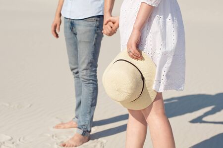 Beautiful couple walking in the mountains. Girl holding a straw hat in her hands, enjoying the sunsetの写真素材