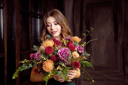 Halloween party girl. Happy Halloween beautiful girl in a black top and a full skirt in her hands holds a bouquet with autumn flowersの写真素材
